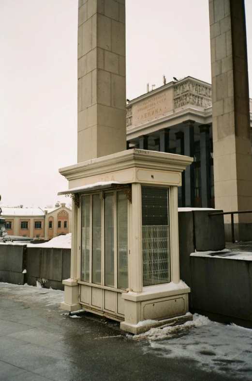 a tall clock tower sitting on top of a snow covered roof, inspired by Carel Willink, neoclassicism, skybridge towers, tall door, outside enclosure, sits on a rooftop