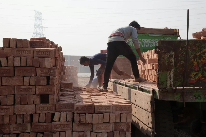 a couple of men standing on top of a pile of bricks, vastayan, profile image, crates and parts on the ground, thumbnail