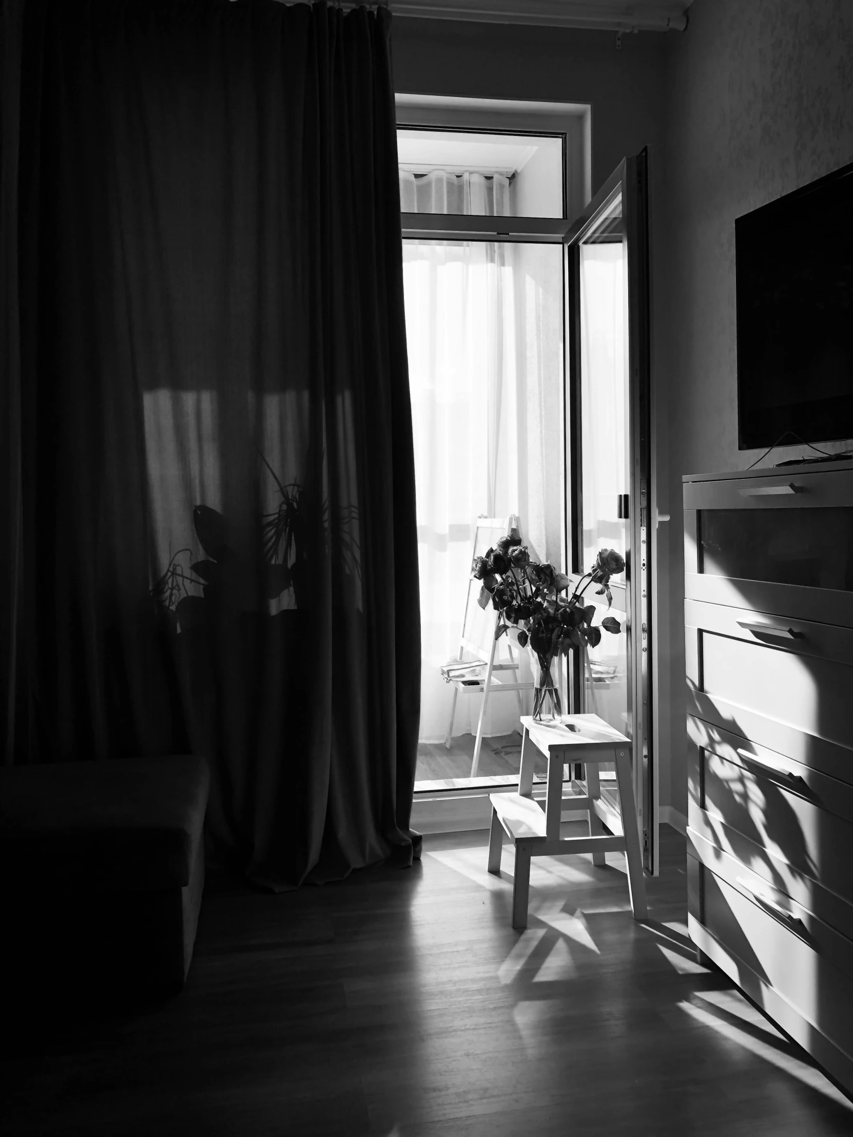 a black and white po of a bedroom with sun shining through the window