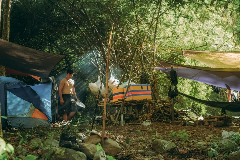 a man sitting in a hammock in the woods, by Elsa Bleda, makeshift houses, breakfast at las pozas, profile image, tents