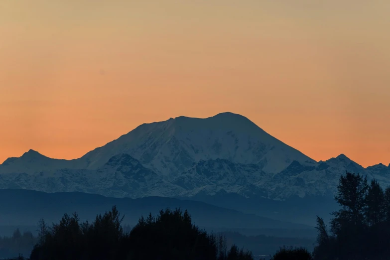 a mountain with trees and a sky in the background