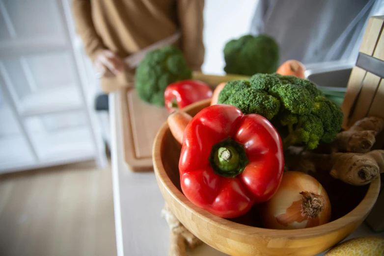 a wooden bowl filled with vegetables on top of a counter, pexels contest winner, looking across the shoulder, archille superbi, at home, green and red