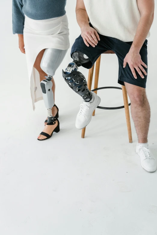 a man sitting on a stool next to a woman, by Adam Marczyński, trending on unsplash, robotic prosthetic limbs, on a white table, upper and lower body, lightly dressed