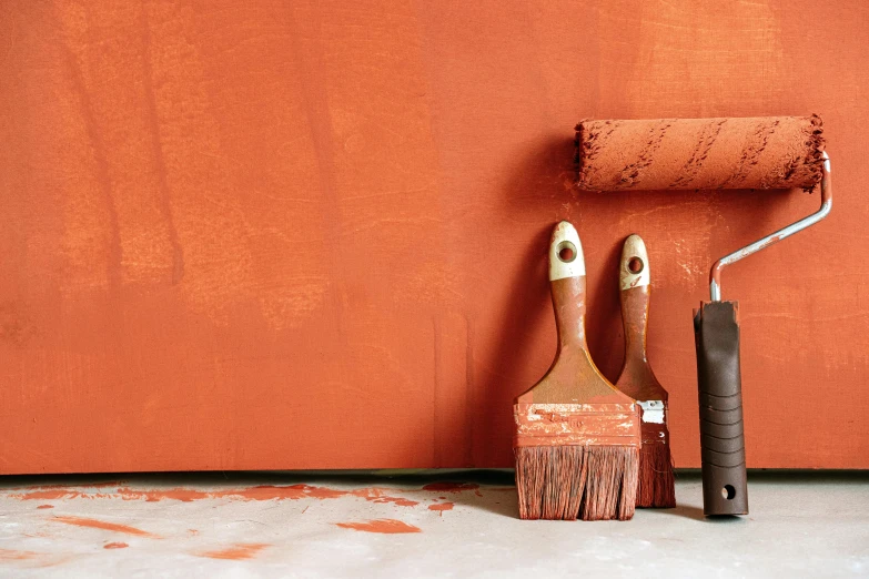 a couple of paint brushes sitting next to a wall, inspired by Mark Rothko, trending on pexels, process art, dark orange, terracotta, no - text no - logo, warm colored furniture