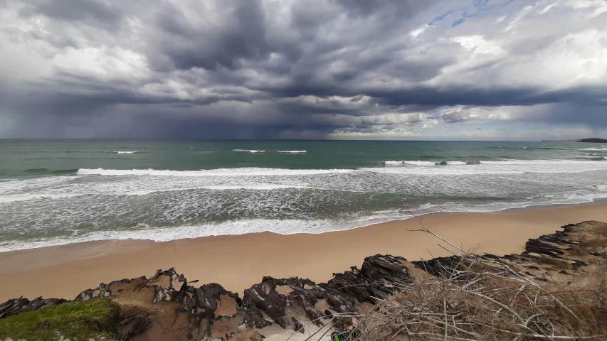 beach on cloudy day with surf board under storm clouds