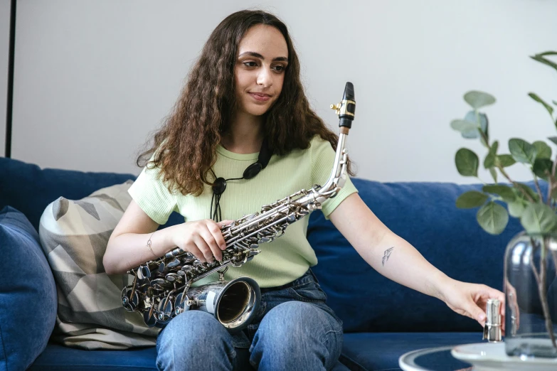 a woman sits on the couch with a saxophone in her hand