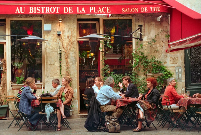 a group of people sitting at tables outside of a restaurant, by Daniel Gelon, french features, fan favorite, in 2 0 0 2, olivier ledroit