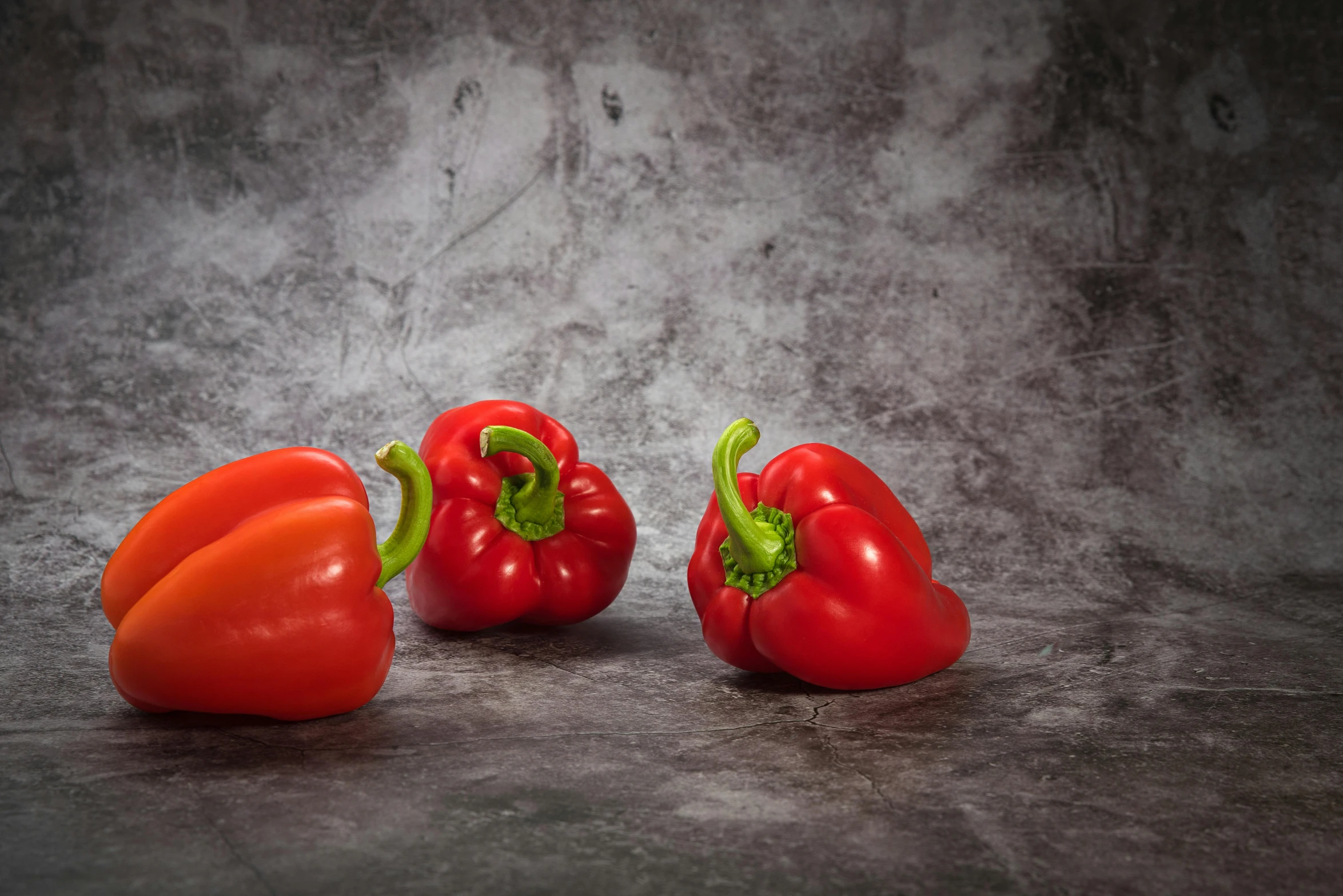 three peppers sitting next to each other on a table, inspired by Jules Robert Auguste, shutterstock contest winner, dark grey backdrop studio, bright red, studio medium format photograph, grey