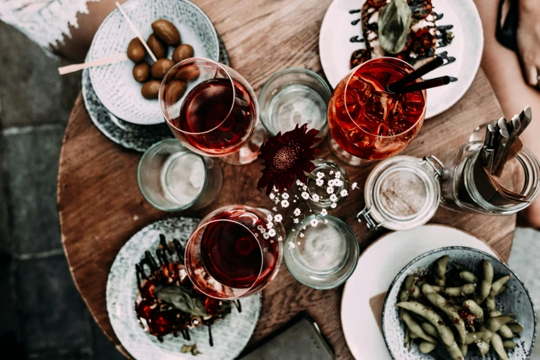 a table topped with plates of food and glasses of wine, pexels contest winner, botanicals, reds, thumbnail, post grunge