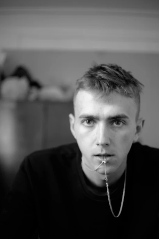 a man with piercing in his mouth sitting next to the table