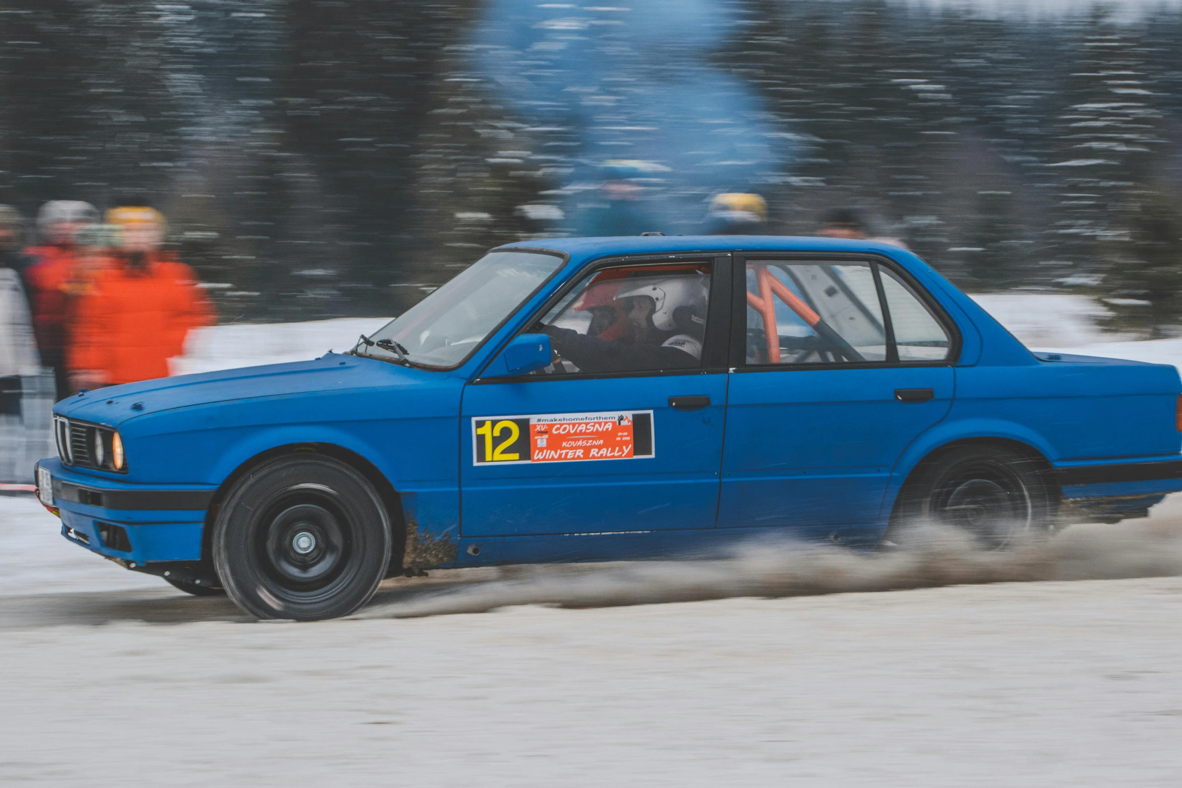 the small car drives down the snow covered road