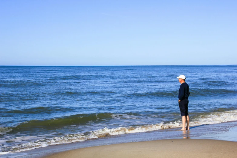 a man standing on top of a beach next to the ocean, caulfield, profile image
