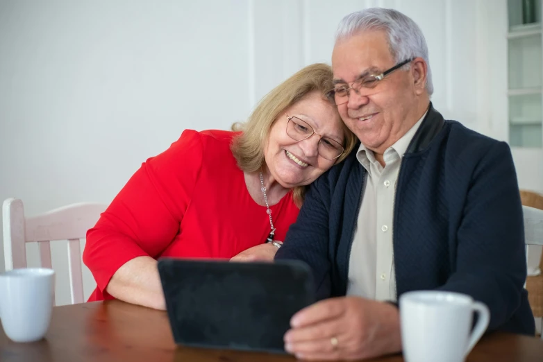 a man and woman sitting at a table looking at a tablet, a portrait, by Julian Allen, pexels contest winner, elderly, 15081959 21121991 01012000 4k, 2 5 6 x 2 5 6 pixels, group photo