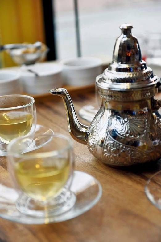 a silver tea pot sitting on top of a wooden table, arabesque, wine, photograph credit: ap, square, food