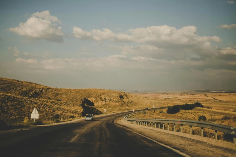 a car driving down the middle of a country road, pexels contest winner, rolling hills, 🚿🗝📝, simple nostalgic, aykut aydogdu