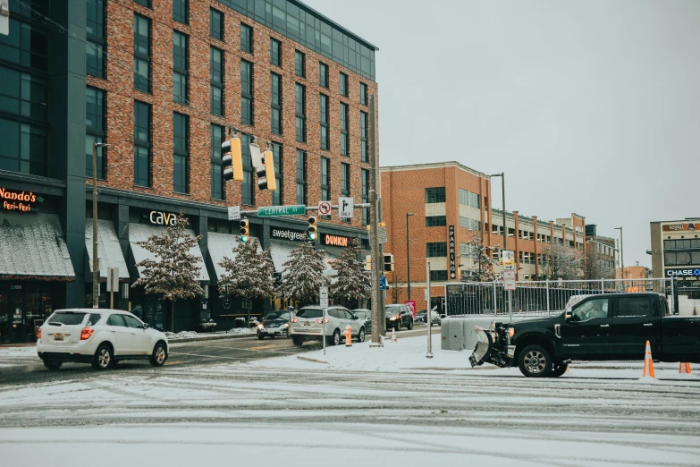 a street filled with lots of traffic next to tall buildings, by Carey Morris, unsplash, southdale center, snow on the body, chesterfield, storefronts