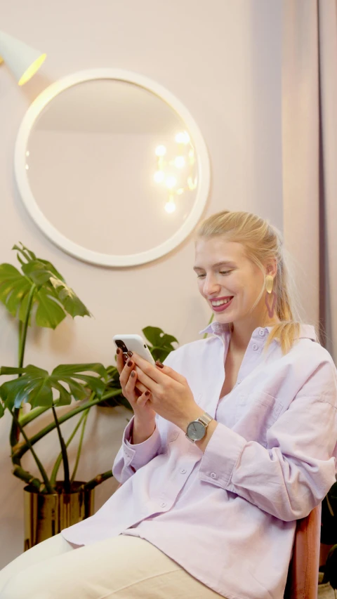 a woman sitting in a chair looking at her cell phone, pexels, golden ratio jewelry lights, avatar image, blonde crea, round mirror on the wall