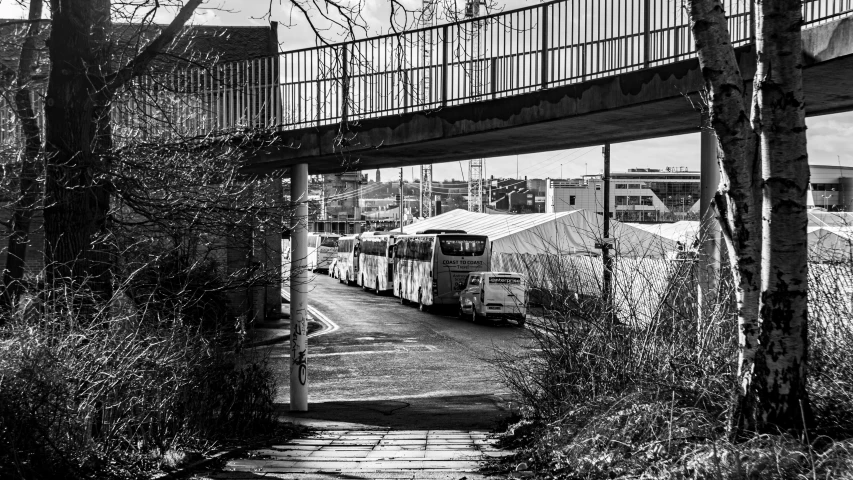 a black and white po of a bus driving under an overpass