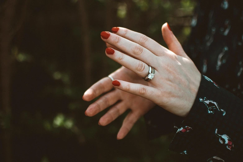 a close up of a person with a ring on their finger, pexels, her hands are red roots, outdoor photo, nail polish, ad image