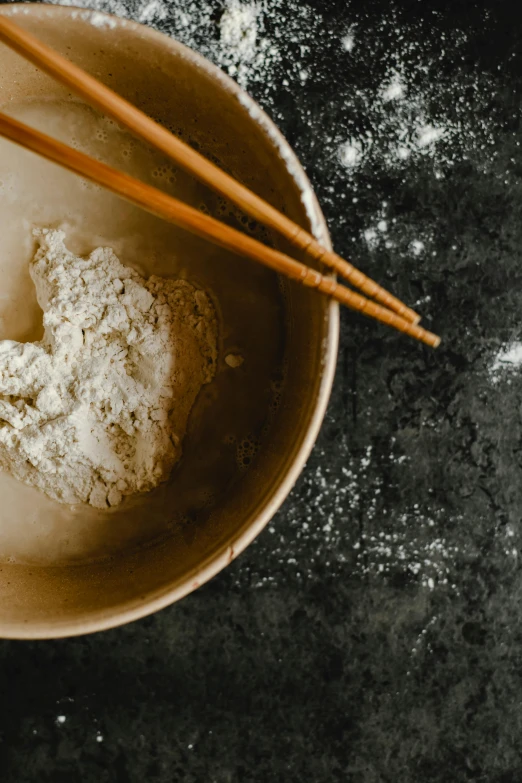 a bowl of food with chopsticks in it, a portrait, trending on unsplash, process art, flour dust, square, kitchen counter, grey