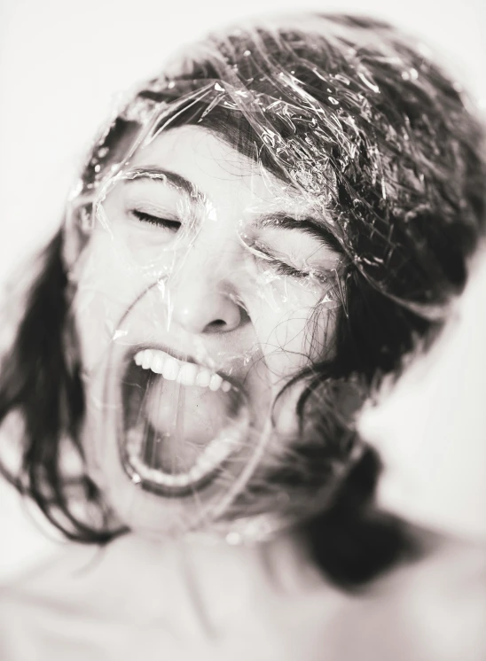 a black and white photo of a woman with her mouth open, inspired by Cornelia Parker, trending on pexels, plasticien, frosting on head and shoulders, plastic wrap, amused, transparent goo