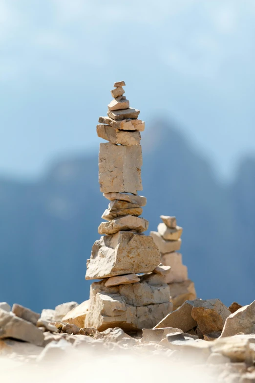 a pile of rocks sitting on top of a sandy beach, an abstract sculpture, inspired by Andy Goldsworthy, unsplash, in the dolomites, tall spires, miniature photography closeup, skyline