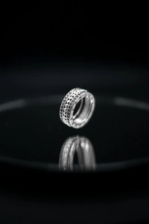 a silver ring sitting on top of a black plate, highly microdetailed, hasselblad film bokeh, intricate highly detailed 8 k, bead and reel