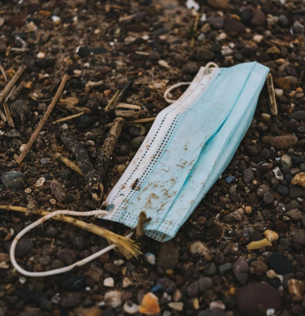 a medical mask laying on the ground surrounded by stones