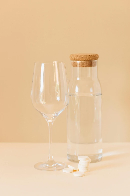 a bottle of water and a wine glass on a table, detailed product image, hero shot, glass cover, large tall