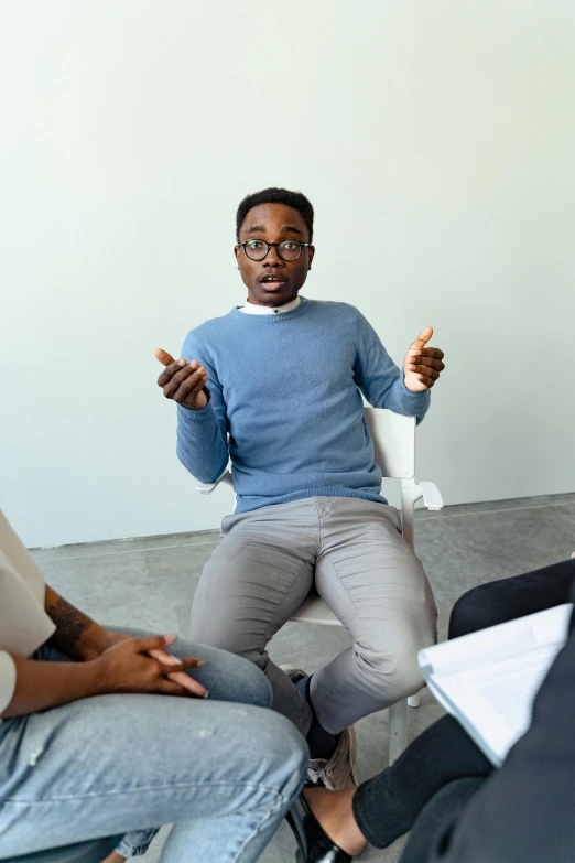 a group of people sitting in a circle talking, black man, man with glasses, stressing out, sitting on a chair