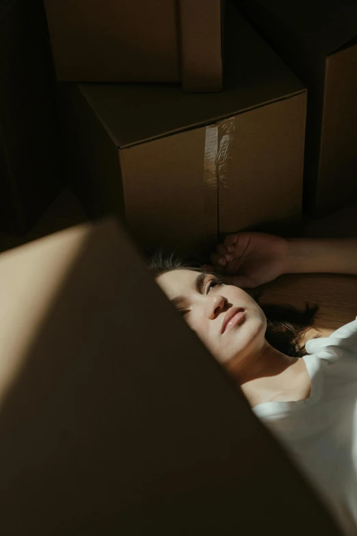 a woman laying on the floor surrounded by boxes, inspired by Elsa Bleda, pexels contest winner, portrait of depressed teen, gif, low sun, ignant