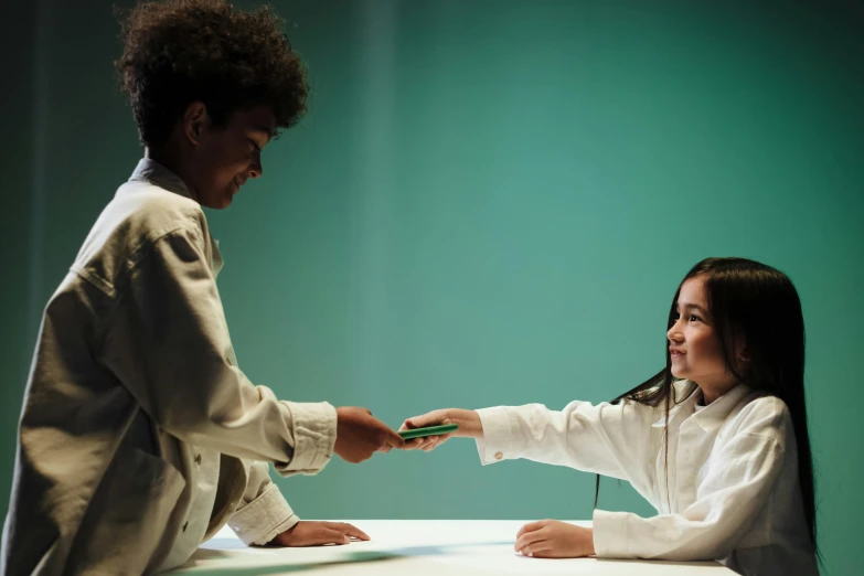 a woman shaking another woman's hand over a table, by artist, interactive art, sea - green and white clothes, photographed for reuters, mixed race, ( ( theatrical ) )