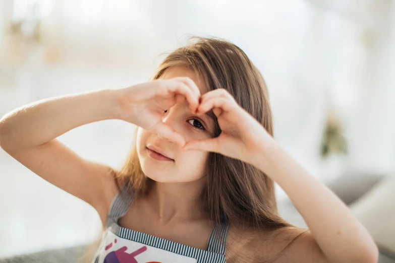 a little girl making a heart with her hands, pexels contest winner, 1 6 years old, attractive, ekaterina, delicious