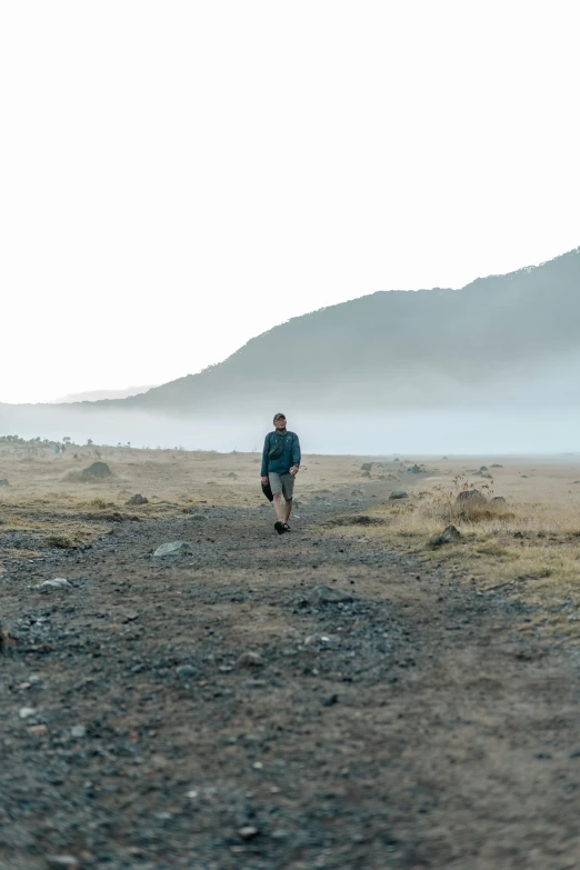 a man in a hat is walking on a dirt road