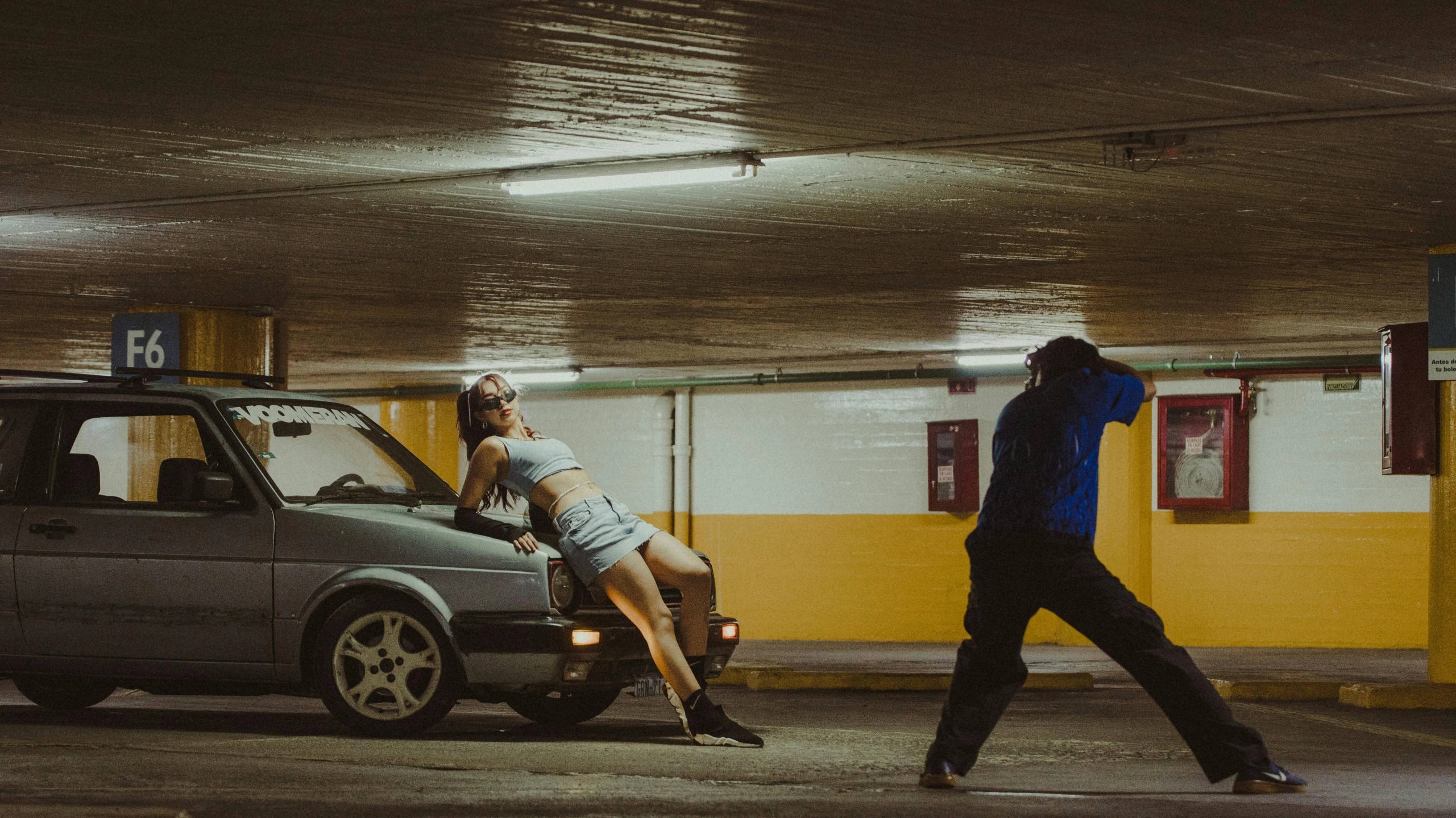 a man standing next to a car holding his leg on another car