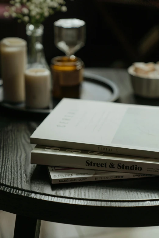 a stack of books sitting on top of a table, a still life, pexels contest winner, private press, cafe tables, silver，ivory, dwell, long street