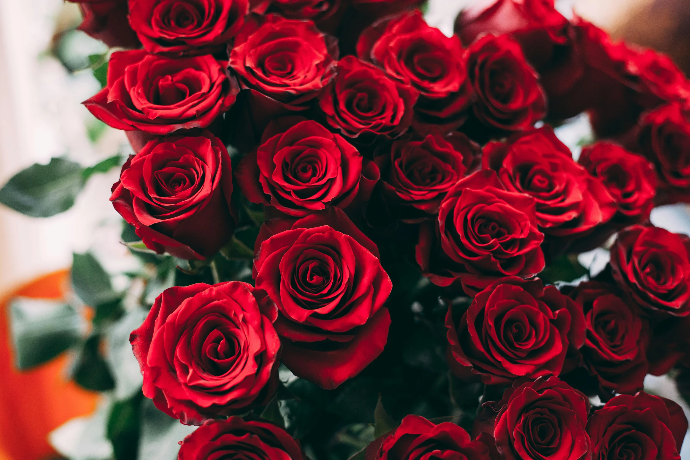 bunch of red roses sitting on top of a desk