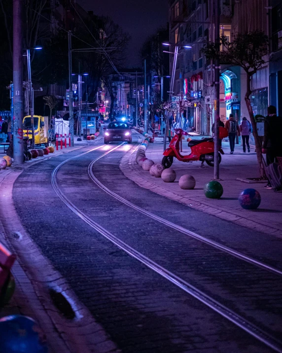 street in front of buildings at night with a car and trolley