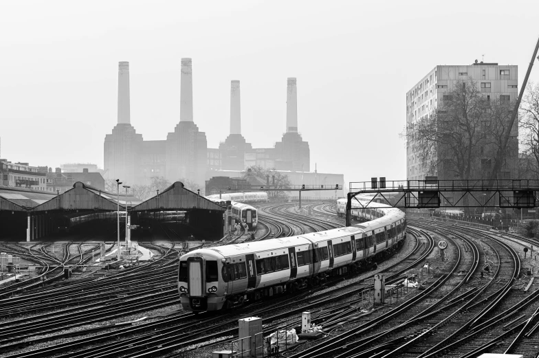 a black and white photo of a train on the tracks, by Andrew Bell, unsplash contest winner, the shard, power plants with smoke, white pale concrete city, springtime morning