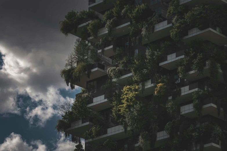 the tall apartment building has vertical windows and green plant life on it's balconies