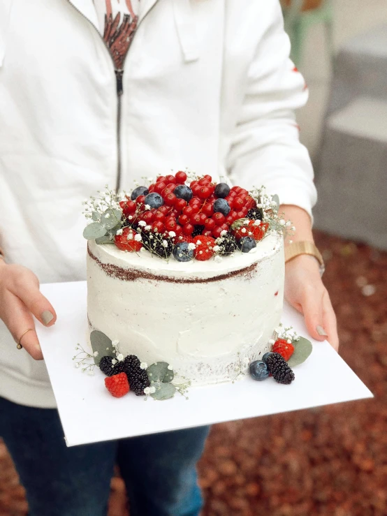 a woman holding a cake with berries on it, by Emma Andijewska, instagram contest winner, silver white red details, 🐿🍸🍋, full product shot, frosted