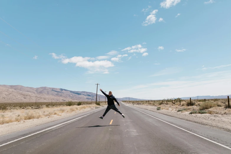 a person jumping in the air on a road, by Julia Pishtar, death valley, background image, artisanal art, cute photo