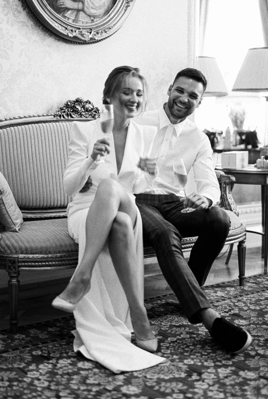 a man and a woman sitting on a couch, a black and white photo, laughing groom, kylie minogue, reza afshar, themed after wine