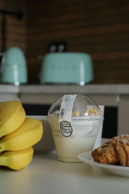 a table topped with a plate of croissants and a cup of coffee, by Daarken, bananas, yogurt, mini model, lots de details