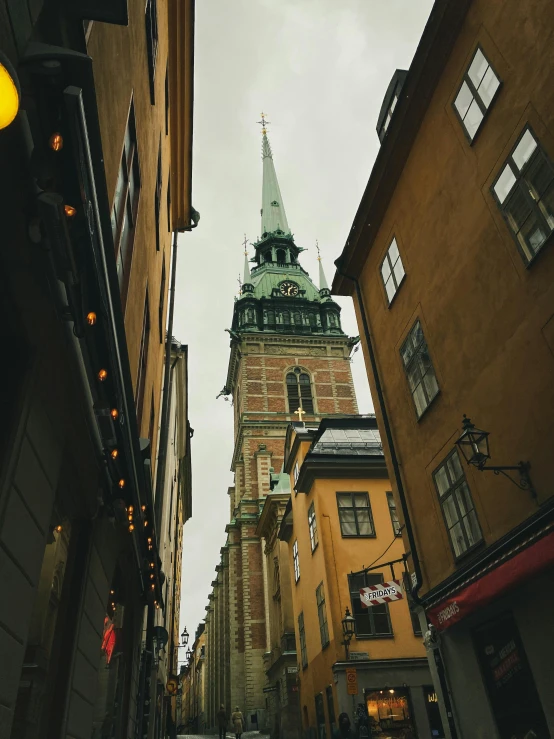 a tall clock tower towering over a city street, by Tom Wänerstrand, pexels contest winner, swedish style, gold and green, dark gloomy church, 🚿🗝📝