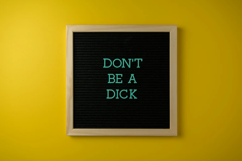 a sign that says don't be a dick on a yellow wall, trending on pexels, blackboard, contracept, digital artwork, wood print