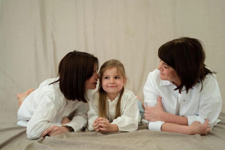 two women and a little girl laying on a bed, a picture, by Attila Meszlenyi, pexels contest winner, wearing lab coat and a blouse, profile image, brown, indoor picture