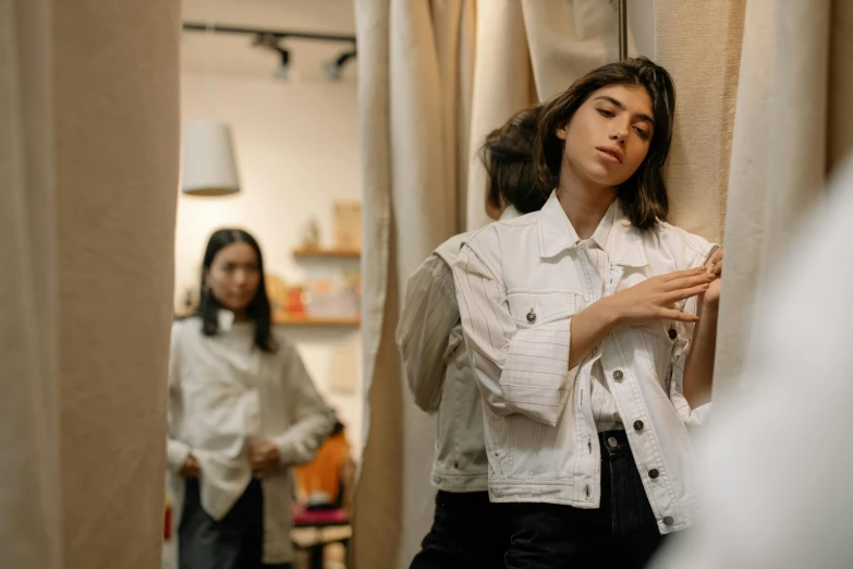 a woman standing next to a curtain in a room, trending on pexels, realism, wearing a jeans jackets, 3 sisters look into the mirror, wearing white clothes, thumbnail