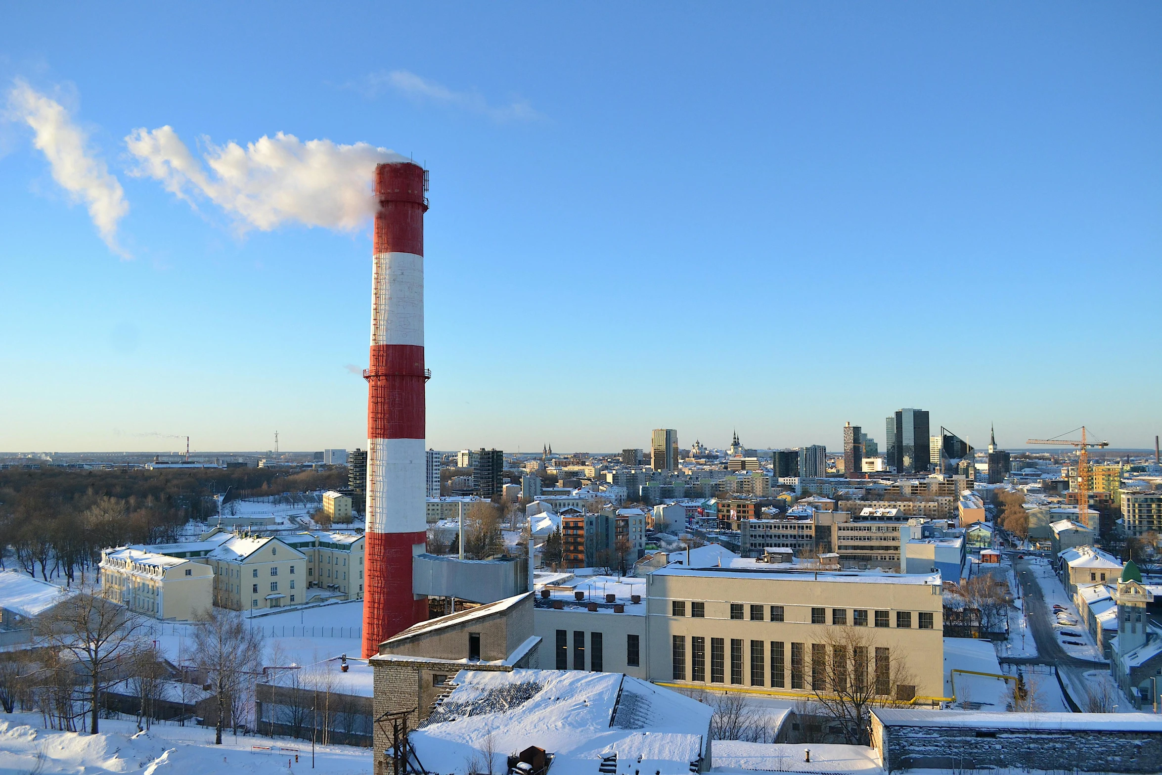 a factory with a lot of smoke coming out of it, by Veikko Törmänen, hurufiyya, towering over a city, blue sky, freezing, chimney