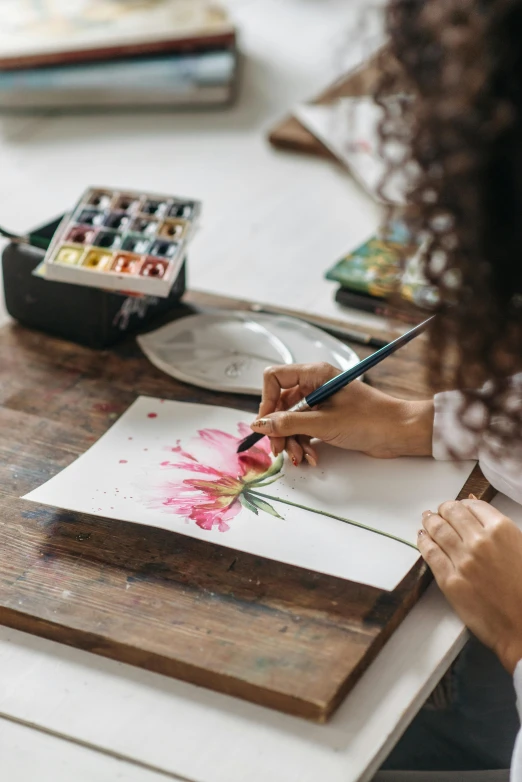 woman with watercolor paint paints on an unfinished piece of paper